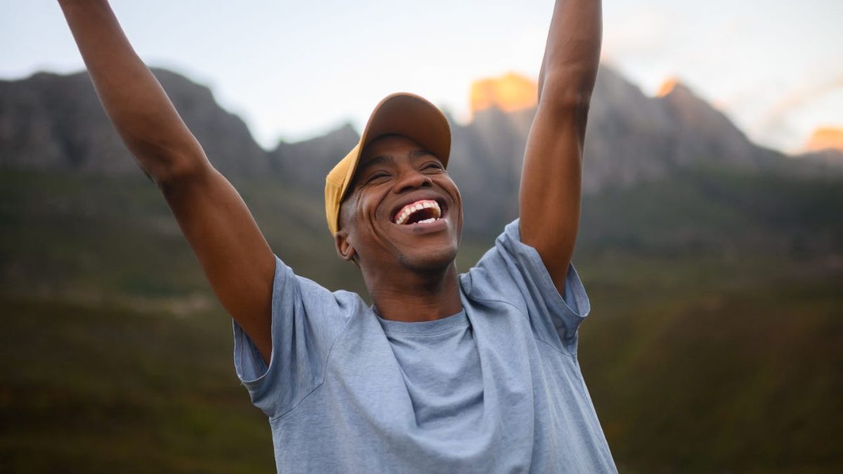 A person outdoors with arms raised, celebrating a sense of financial freedom.